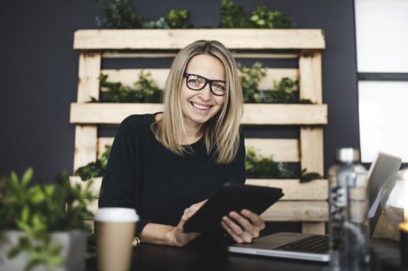 An adult woman smiling at the camera and learning online at UC