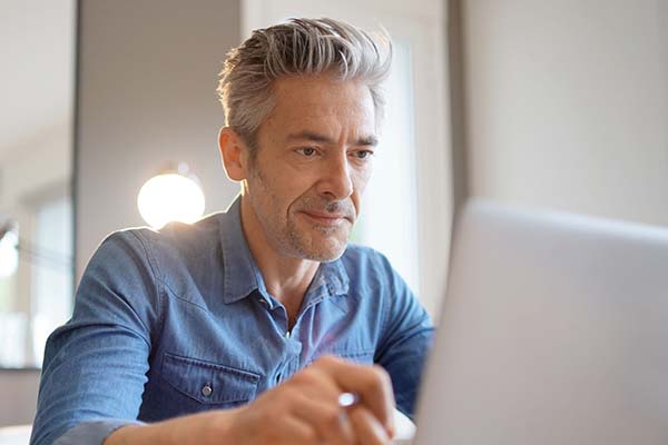 middle-aged UC online student at a desk reading from his laptop