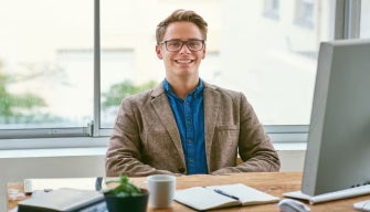 A confident professional man sits at a desk with a computer, representing the qualities of good public policy