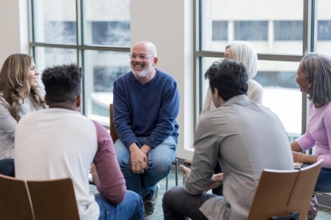 A mental health social worker helping and talking to a group of people.