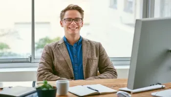 A confident professional man sits at a desk with a computer, representing the qualities of good public policy