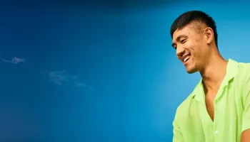 A man wearing a green shirt is smiling warmly at the camera.