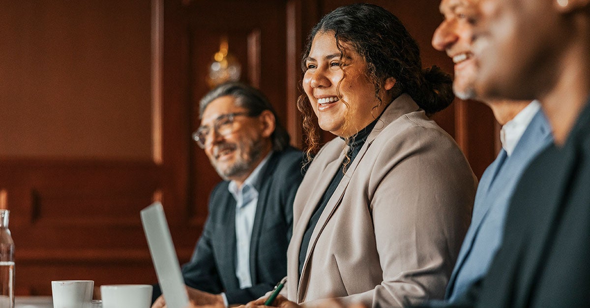 A group of diverse individuals seated at a table, each using a laptop for collaborative work.